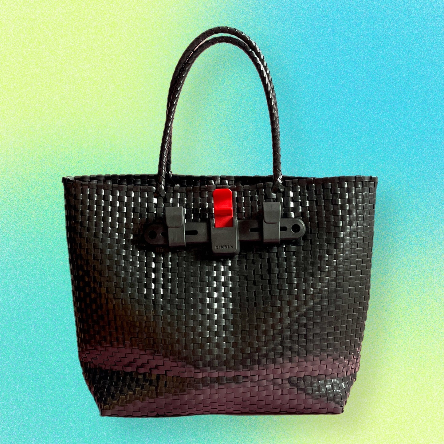 A black plastic woven bicycle pannier basket with red toggle closure, suitable for carrying voluminous items or shopping.