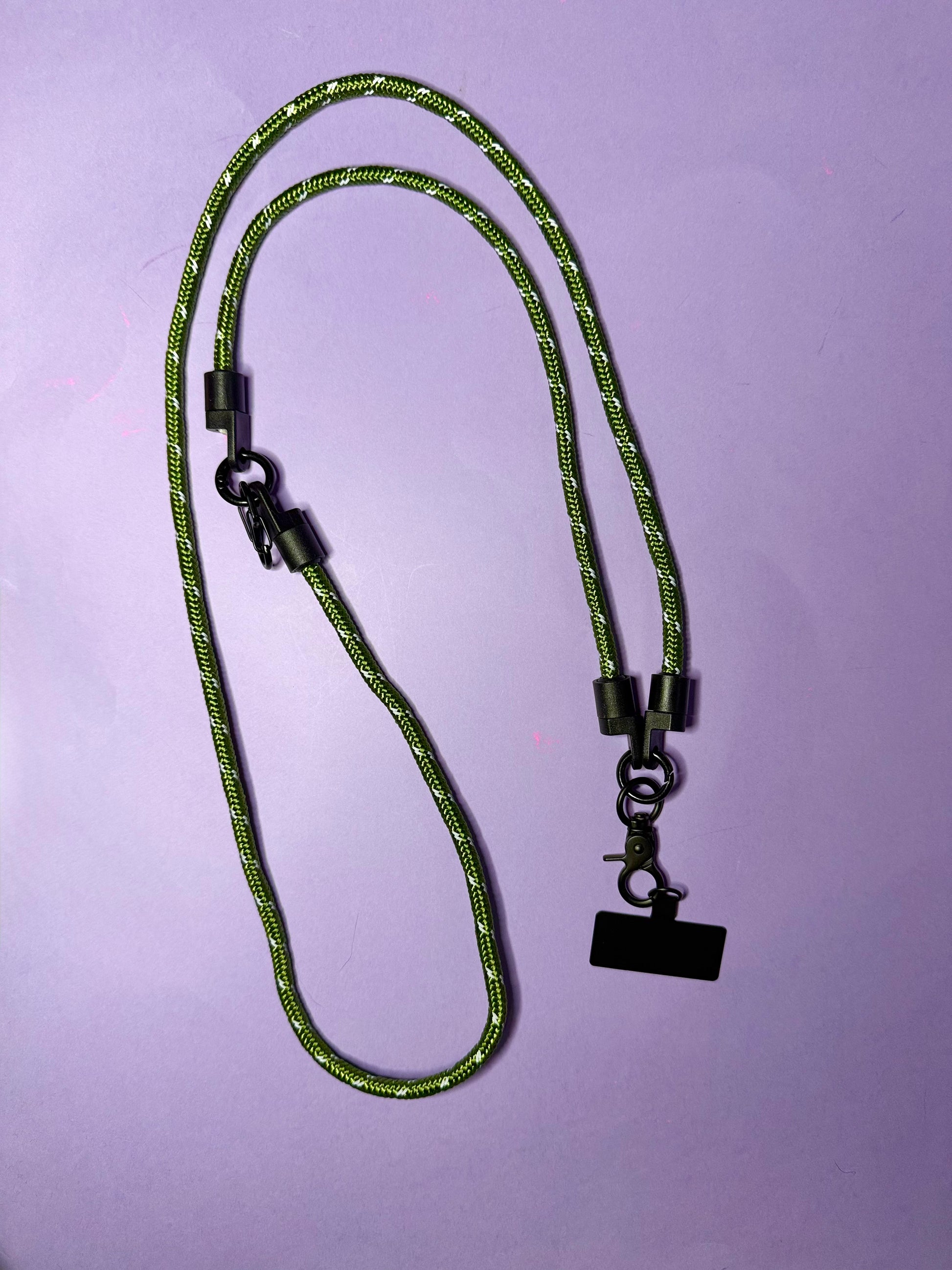 Green braided lanyard with black metal clip on a purple background