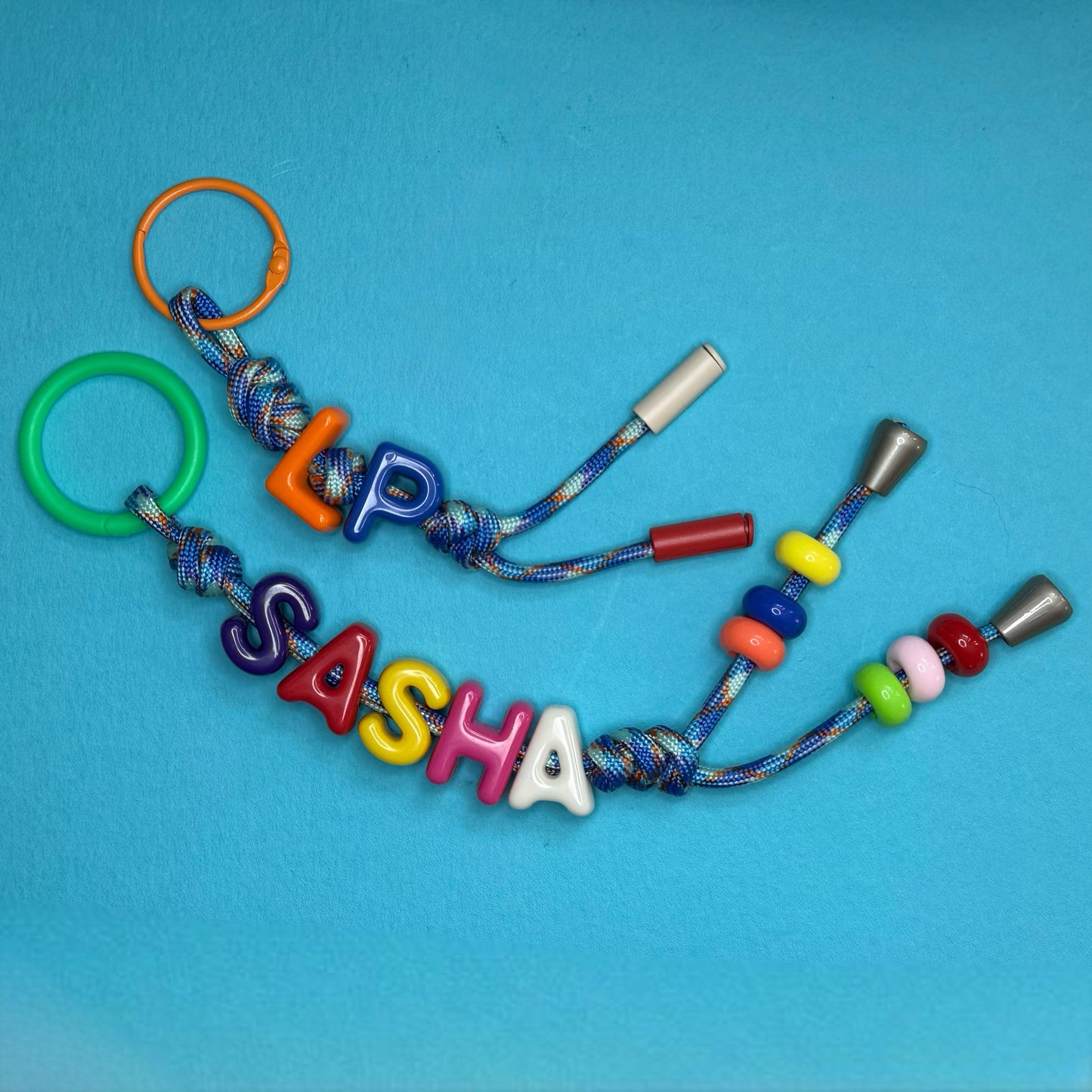 Colorful keychain with letter beads spelling 'LUPASASHA' on a blue background