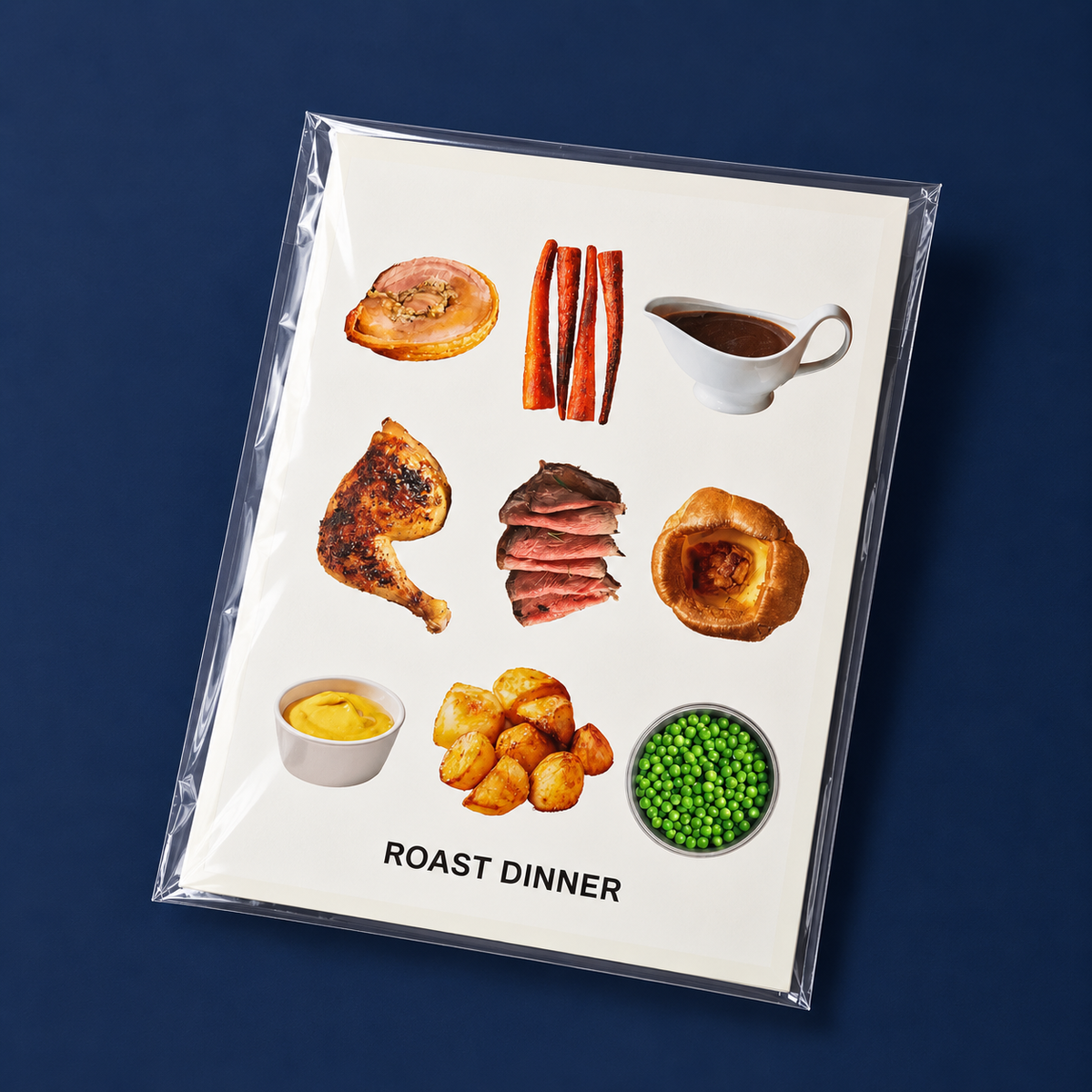 A square art print titled 'ROAST DINNER' in black sans-serif text, featuring a collage of British roast dinner foods on an off-white background, enclosed in a clear plastic sleeve and photographed on a dark navy blue background.