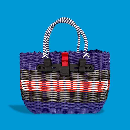 Woven pannier basket with striped handle and red strap on a blue background