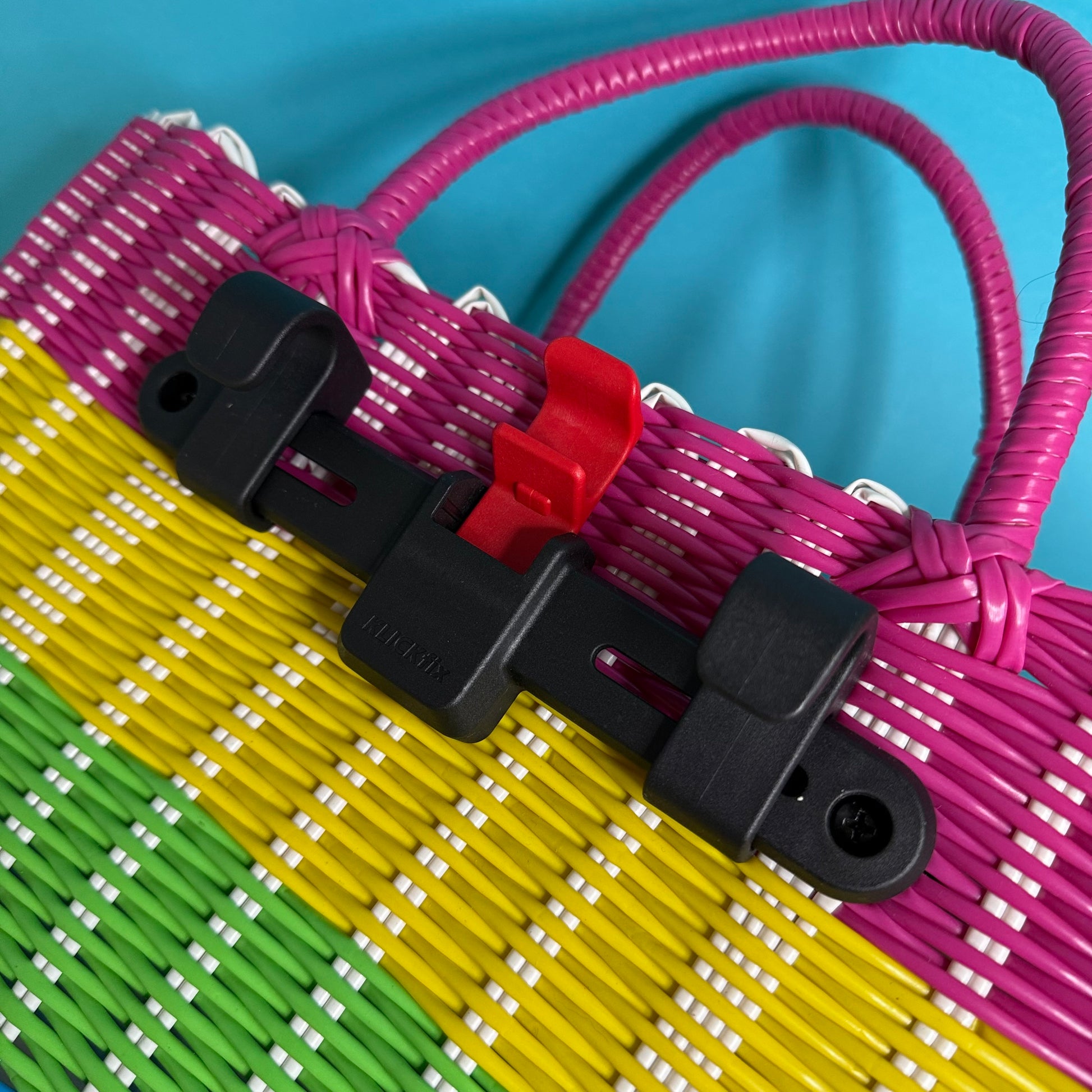 Close-up of a colorful woven mat with a red clip on a blue background