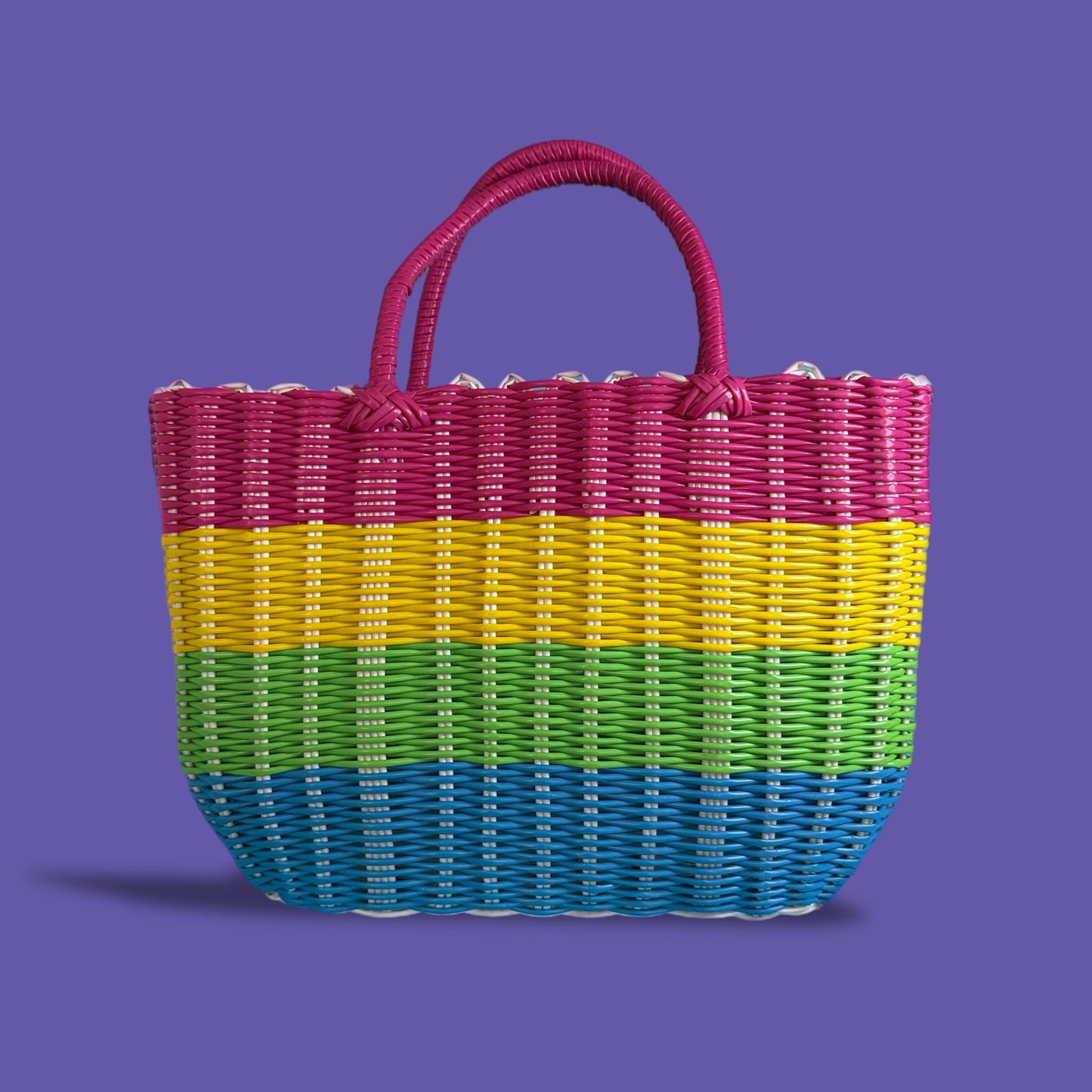 Multicolored woven basket with a pink handle on a purple background