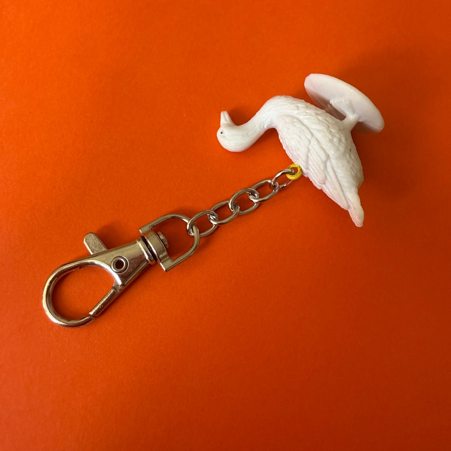 Keychain with a white bird design on an orange background
