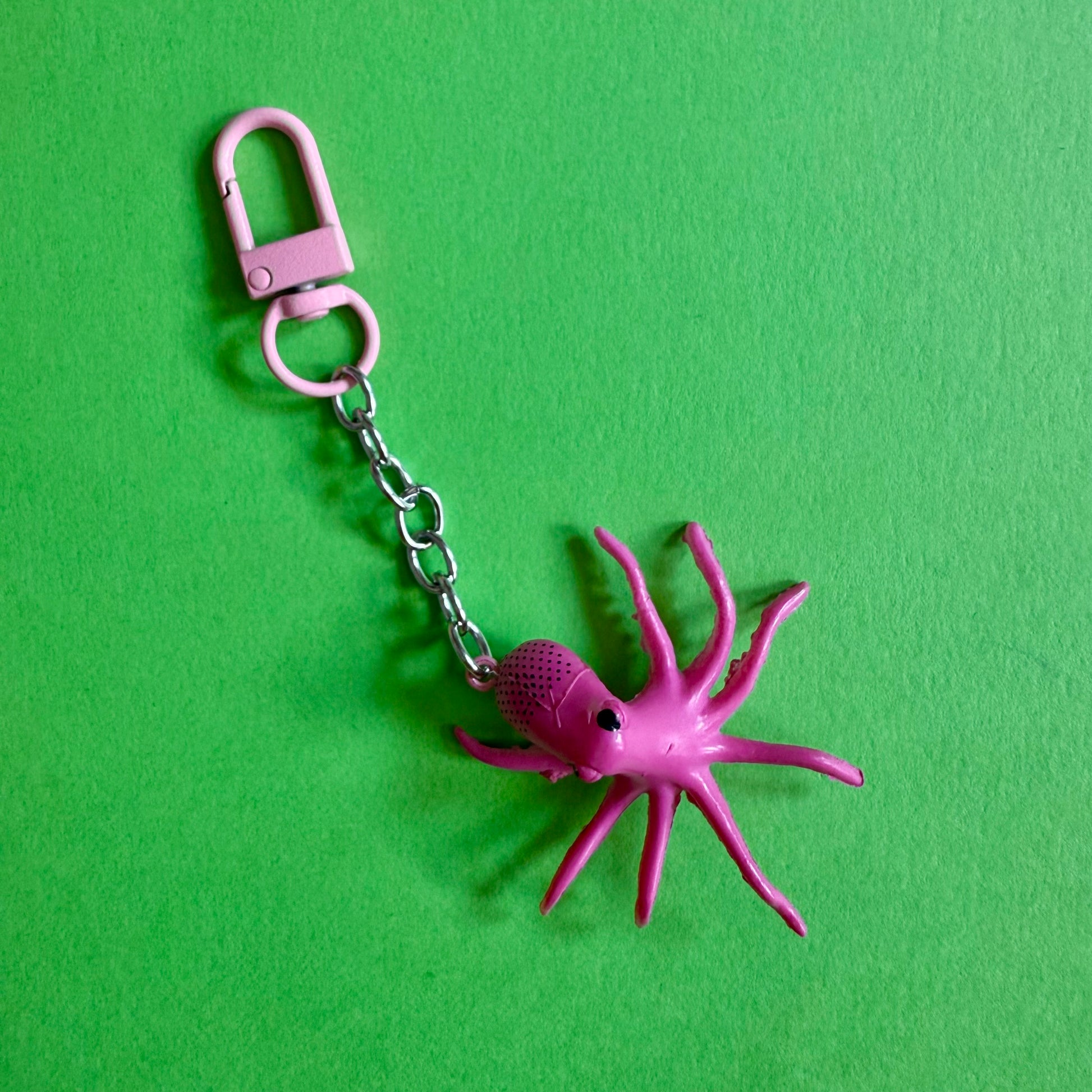 Pink spider octopus keychain on a green background