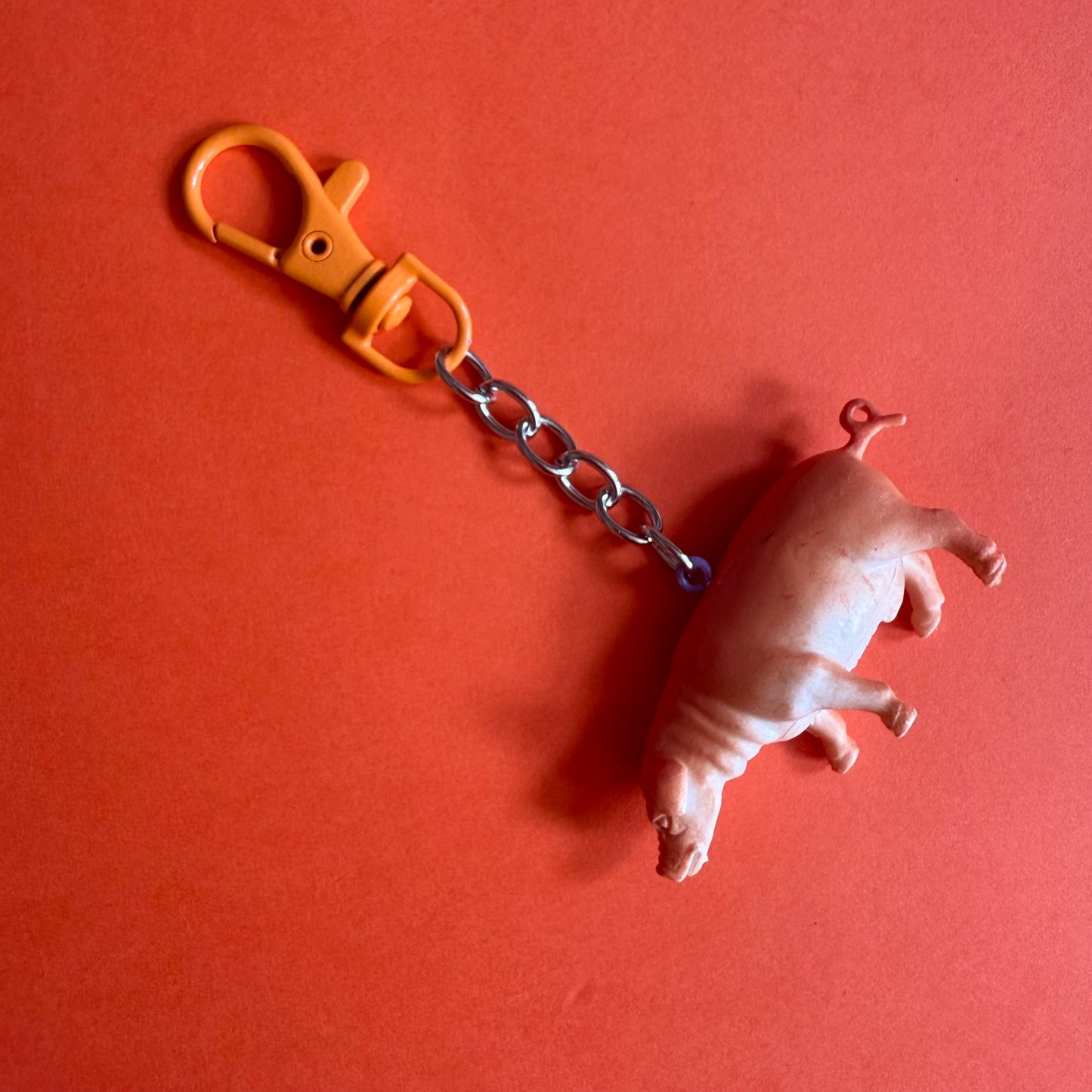 Keychain with pig figure and yellow clip on a red background