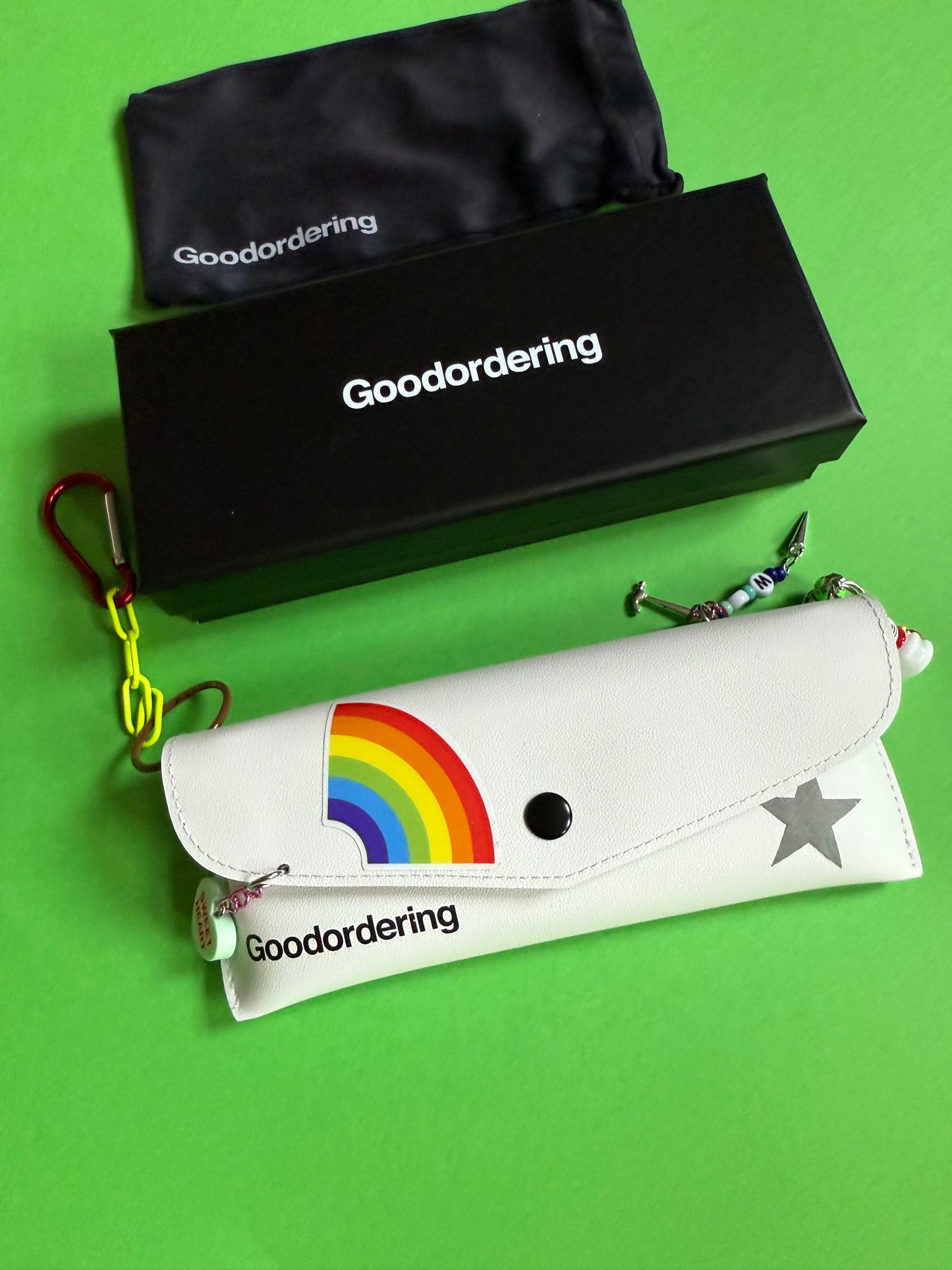 Glasses case with rainbow sticker and charms hanging from it