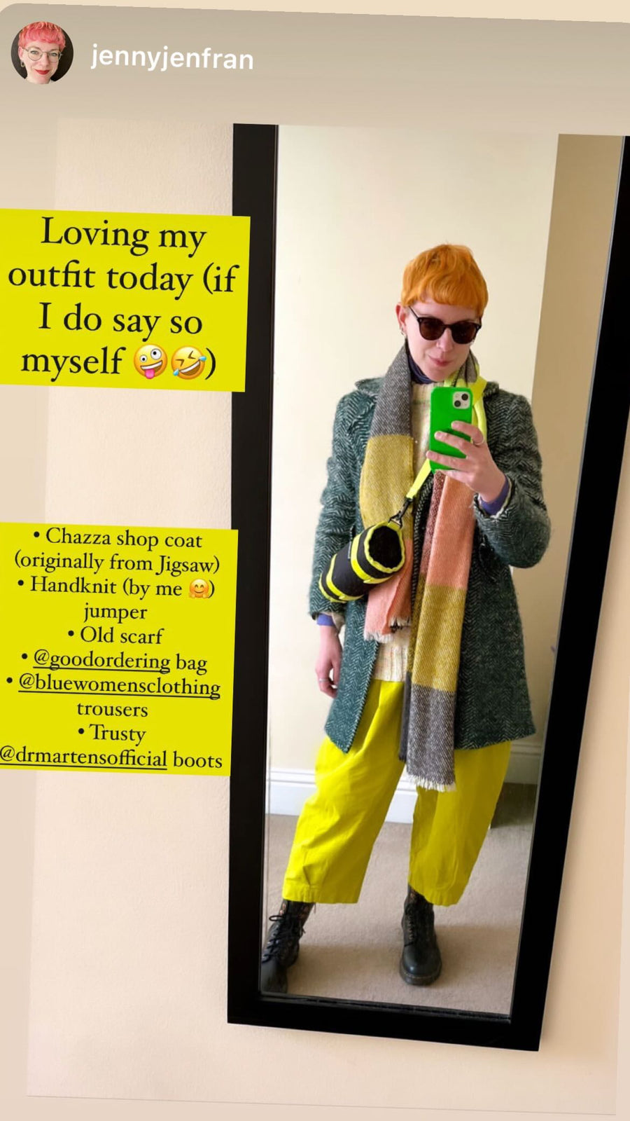 A person taking a mirror selfie in an outfit featuring a green textured coat, a pink and yellow striped scarf, bright yellow trousers, and black boots. The image includes a text overlay detailing the outfit pieces and a yellow sticker on the left.