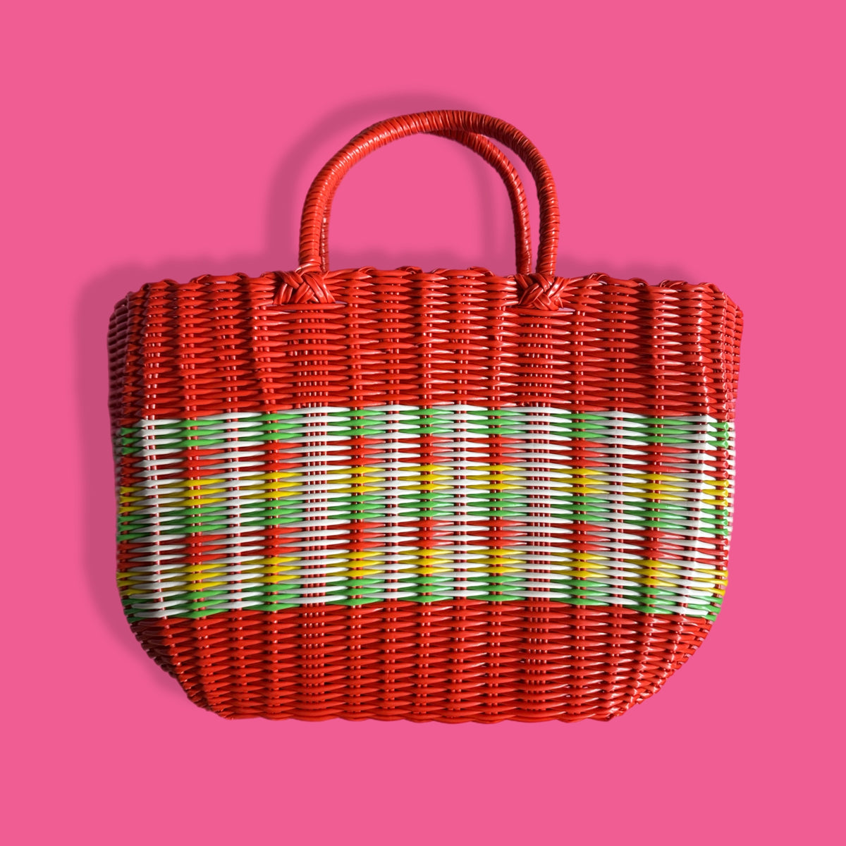 Woven handbag with red frame and multicolored pattern on a pink background