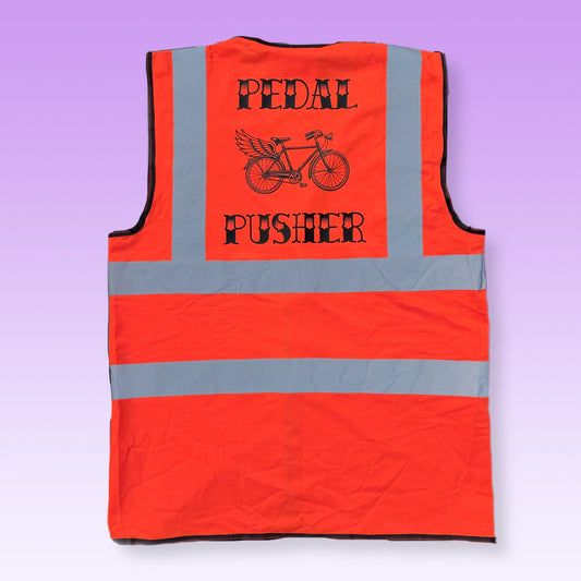 An orange high-visibility safety vest shown from the back, featuring gray reflective stripes and a black graphic of a winged bicycle with the text 'PEDAL PUSHER'.